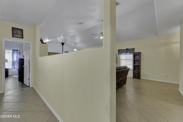 corridor featuring tile patterned flooring, lofted ceiling, a healthy amount of sunlight, and baseboards