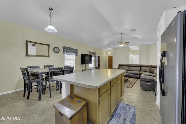 kitchen featuring light tile patterned floors, freestanding refrigerator, vaulted ceiling, light countertops, and a center island