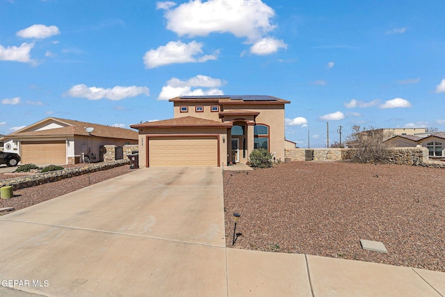 view of front facade featuring a garage, roof mounted solar panels, driveway, and stucco siding