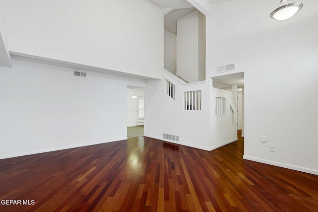 unfurnished living room featuring hardwood / wood-style floors, stairway, baseboards, and visible vents