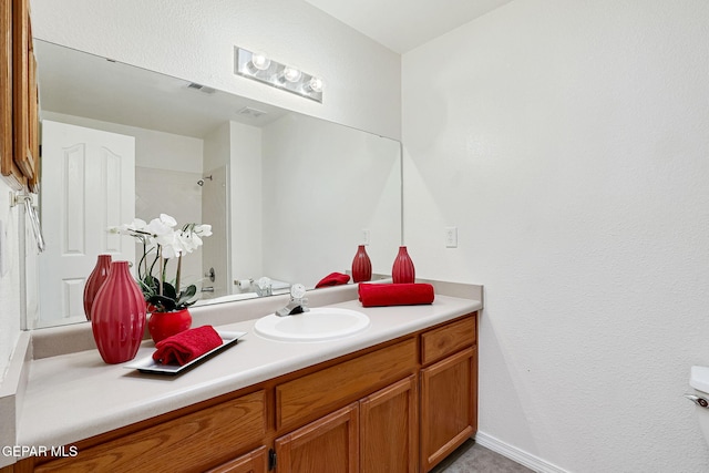 bathroom with visible vents, vanity, and walk in shower