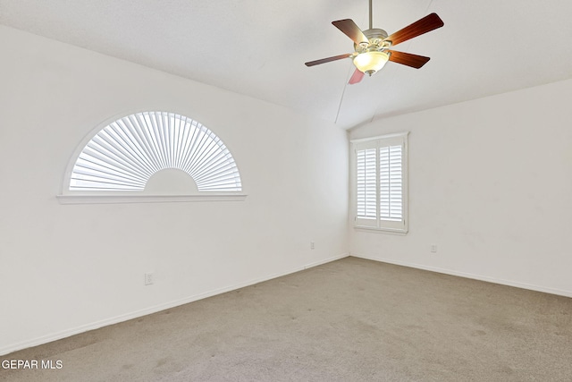 unfurnished room with lofted ceiling, carpet flooring, a ceiling fan, and baseboards