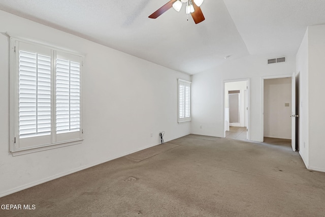 carpeted spare room featuring lofted ceiling, a ceiling fan, and visible vents