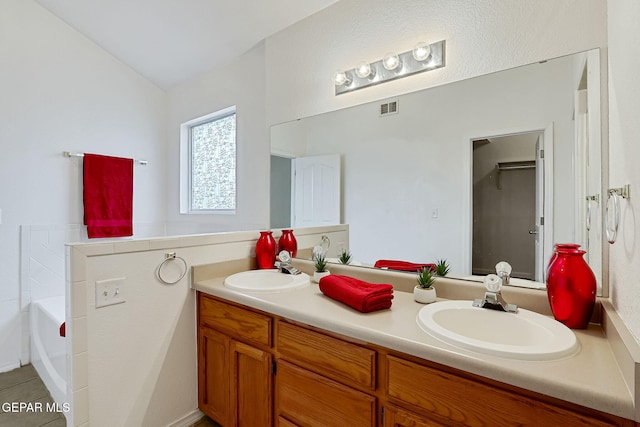 full bathroom with a sink, visible vents, a garden tub, and double vanity