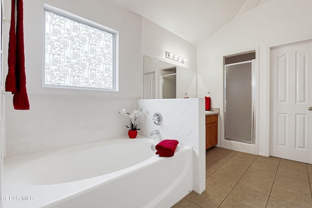 bathroom with tile patterned flooring, vaulted ceiling, a stall shower, a bath, and vanity