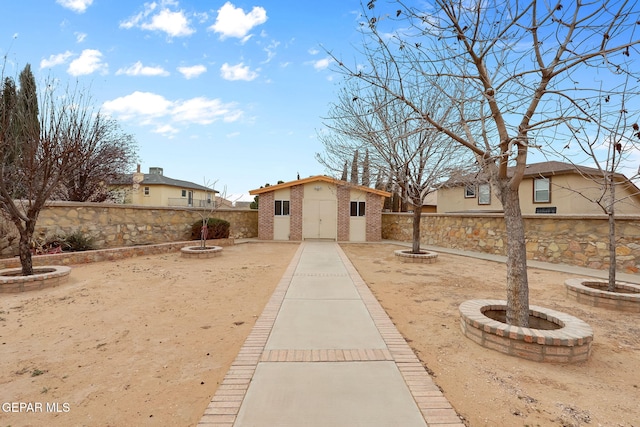 view of yard with an outdoor structure, a fenced backyard, and an outdoor fire pit