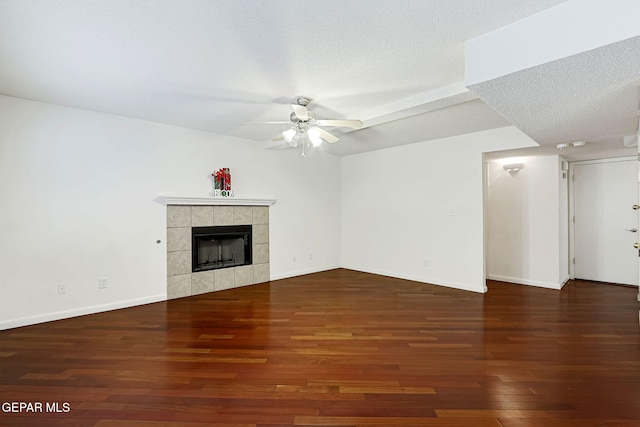 unfurnished living room with ceiling fan, a textured ceiling, wood finished floors, and a tiled fireplace