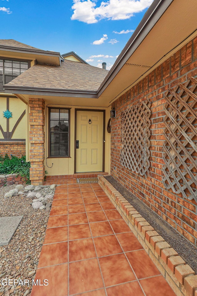 property entrance with brick siding and a shingled roof