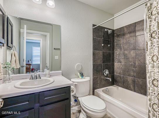 bathroom with shower / bath combo, a textured wall, vanity, and toilet