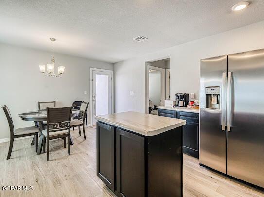 kitchen featuring light wood finished floors, visible vents, stainless steel refrigerator with ice dispenser, and light countertops