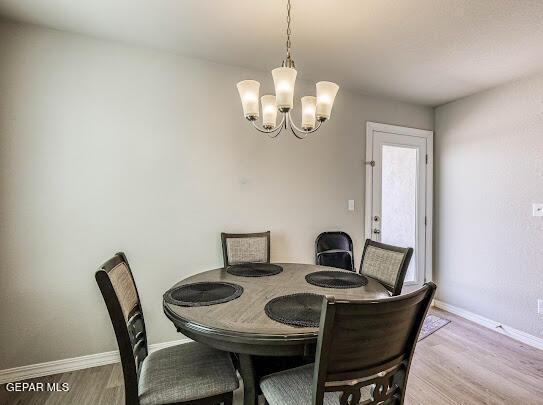 dining room featuring a chandelier, baseboards, and wood finished floors