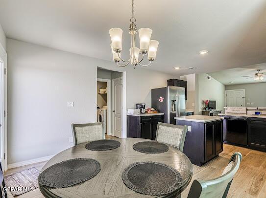 dining area featuring ceiling fan with notable chandelier, light wood-type flooring, baseboards, and washer and dryer