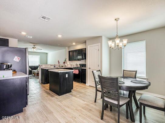 kitchen with black microwave, stove, visible vents, dark cabinetry, and a center island