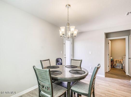 dining room featuring light wood-style floors, a chandelier, visible vents, and baseboards