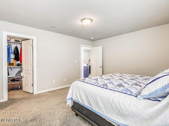 bedroom featuring a spacious closet, baseboards, a closet, and light colored carpet