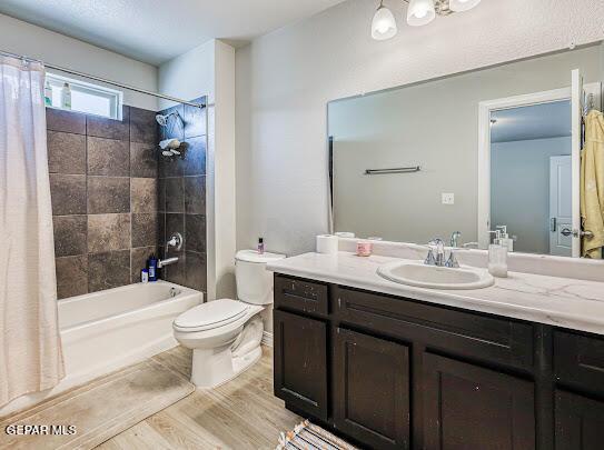 full bath featuring toilet, shower / bathtub combination with curtain, wood finished floors, and vanity