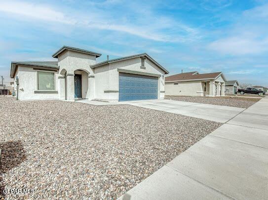 view of front of property with a garage, concrete driveway, and stucco siding