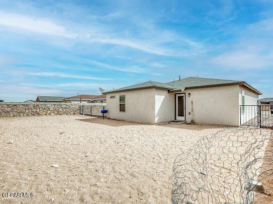 back of house featuring fence and stucco siding