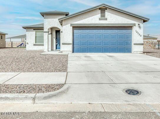 view of front of home featuring driveway, fence, an attached garage, and stucco siding