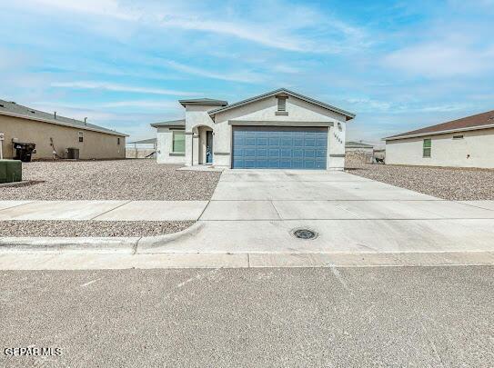 view of front of property featuring concrete driveway, an attached garage, and stucco siding