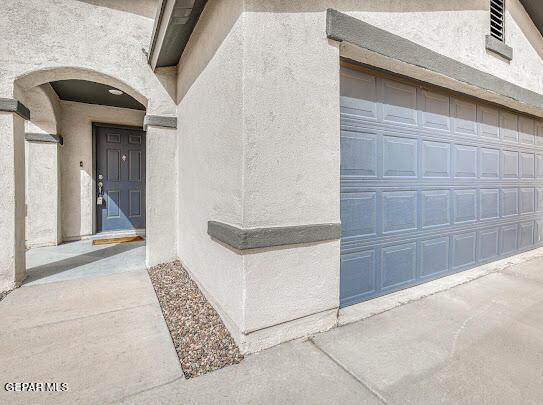 doorway to property featuring concrete driveway and stucco siding