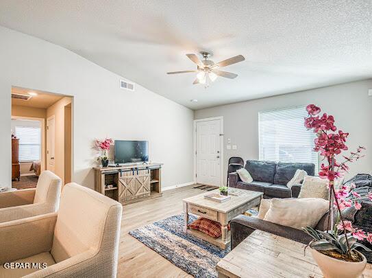 living room with a ceiling fan, lofted ceiling, plenty of natural light, and wood finished floors