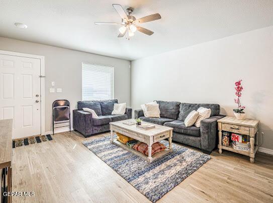 living area featuring light wood finished floors, ceiling fan, and baseboards