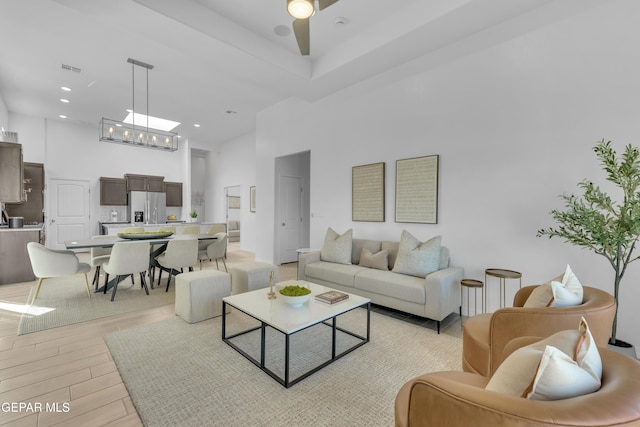 living area with light wood-style floors, visible vents, and a high ceiling