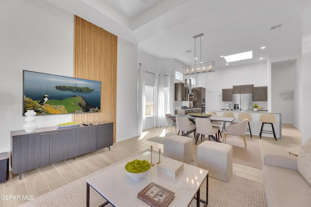 living room featuring recessed lighting, a high ceiling, a skylight, visible vents, and baseboards