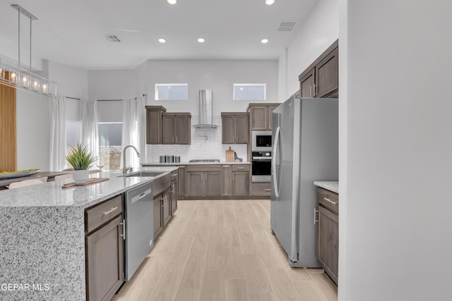 kitchen featuring stainless steel appliances, wall chimney range hood, visible vents, and decorative backsplash