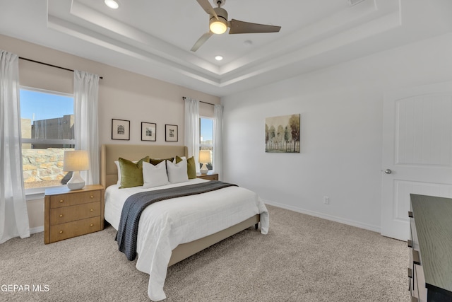 bedroom featuring light carpet, baseboards, and a tray ceiling