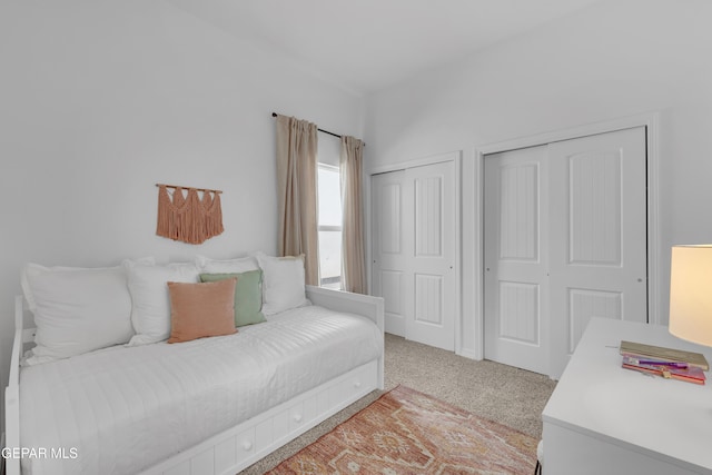 bedroom featuring multiple closets and light colored carpet