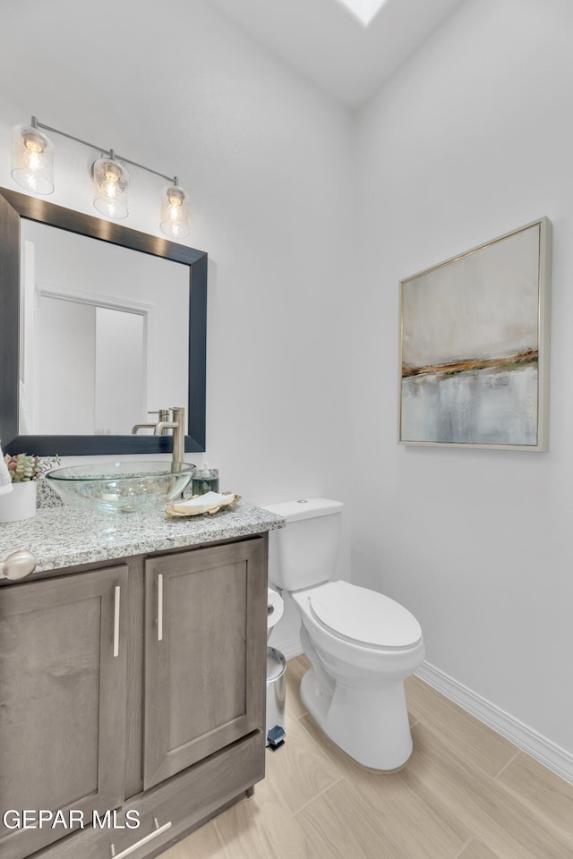 bathroom featuring baseboards, vanity, and toilet