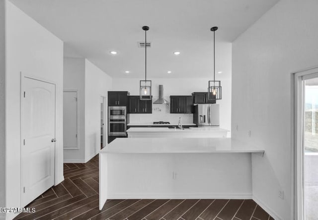 kitchen featuring stainless steel appliances, light countertops, visible vents, a sink, and wall chimney range hood