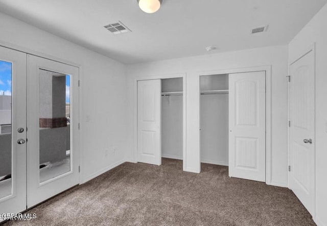 unfurnished bedroom featuring carpet, visible vents, two closets, and french doors