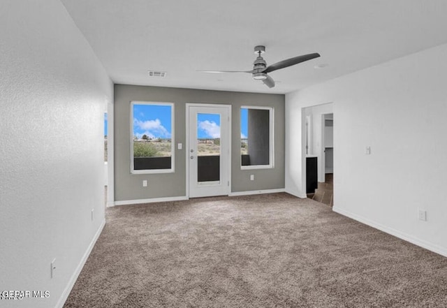 unfurnished room with carpet floors, visible vents, baseboards, and a ceiling fan