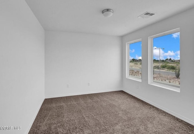 carpeted spare room featuring visible vents and baseboards