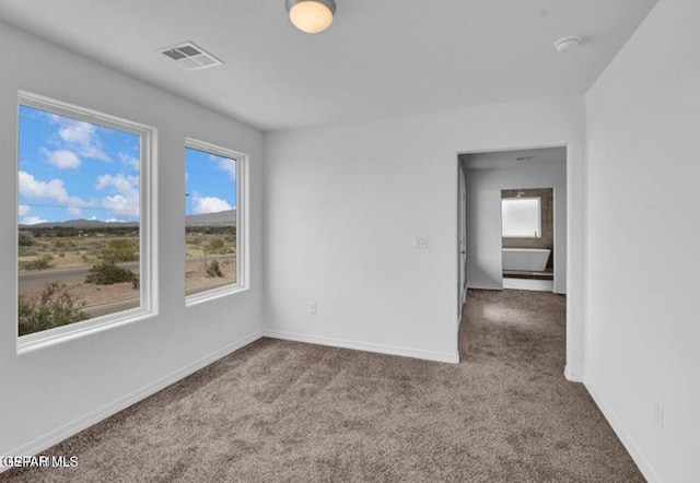 spare room with carpet floors, visible vents, and baseboards