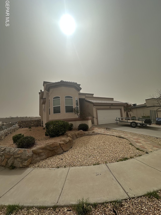 mediterranean / spanish-style home with an attached garage, a tile roof, concrete driveway, and stucco siding