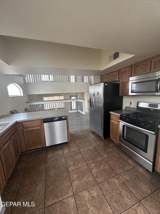 kitchen featuring visible vents, appliances with stainless steel finishes, a textured ceiling, and dark tile patterned flooring