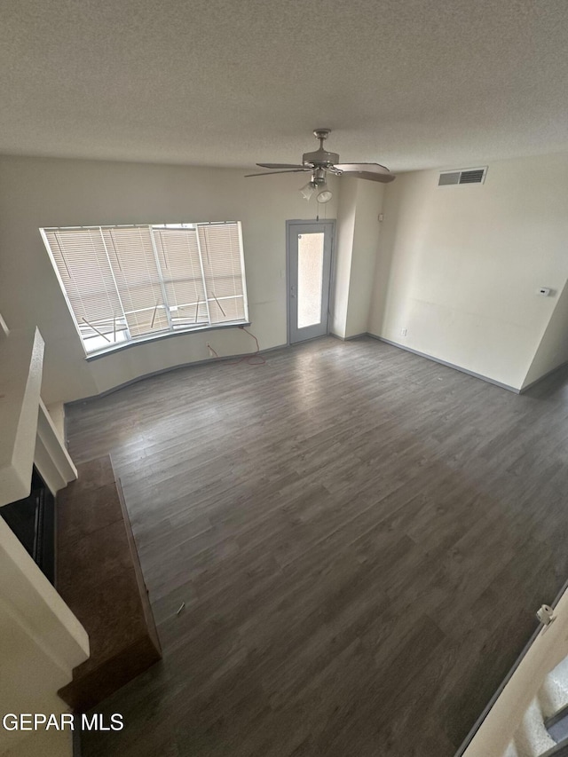 unfurnished living room with a ceiling fan, visible vents, a textured ceiling, and wood finished floors