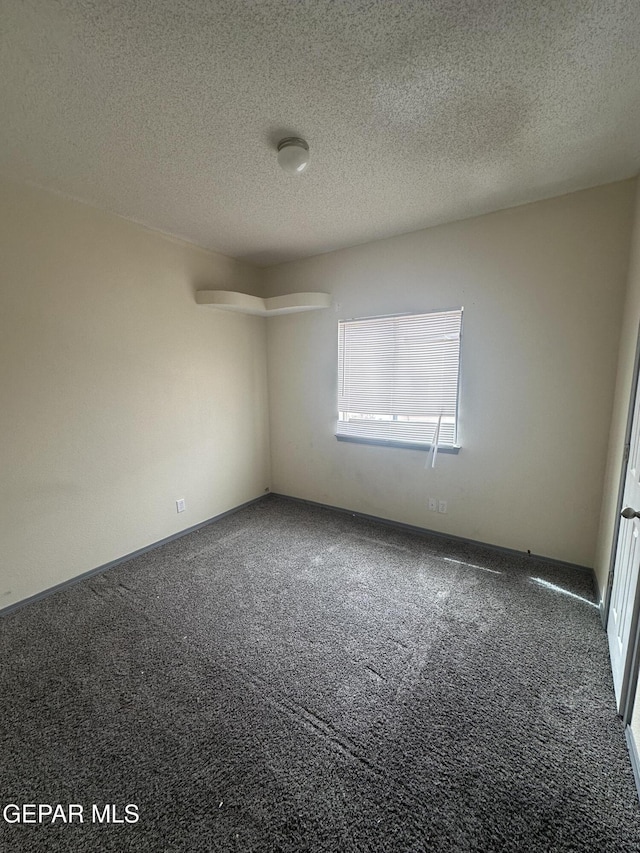 carpeted empty room featuring a textured ceiling and baseboards