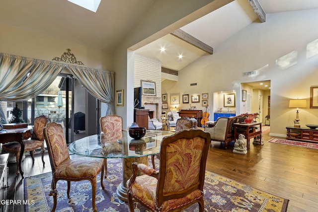 dining area featuring high vaulted ceiling, a skylight, visible vents, hardwood / wood-style floors, and beamed ceiling