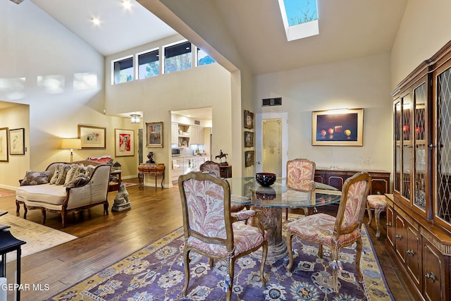 dining area featuring high vaulted ceiling, a skylight, wood-type flooring, and visible vents