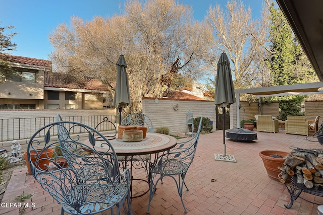 view of patio / terrace with a fire pit, outdoor dining area, and fence