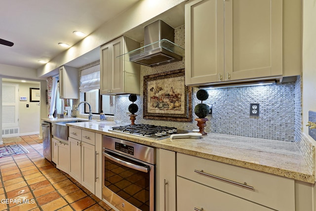 kitchen with tasteful backsplash, visible vents, wall chimney exhaust hood, stainless steel appliances, and a sink