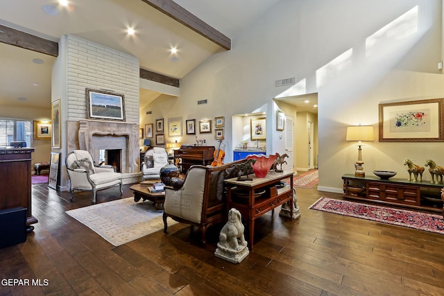 living area with beam ceiling, a fireplace, wood-type flooring, and visible vents