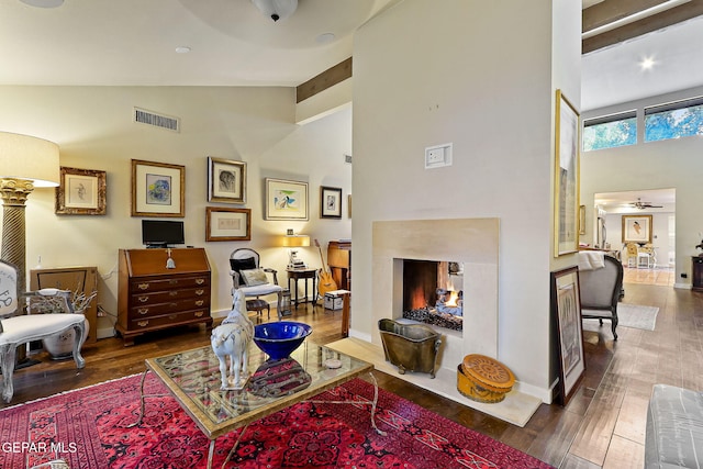 living area featuring high vaulted ceiling, visible vents, wood finished floors, and a multi sided fireplace