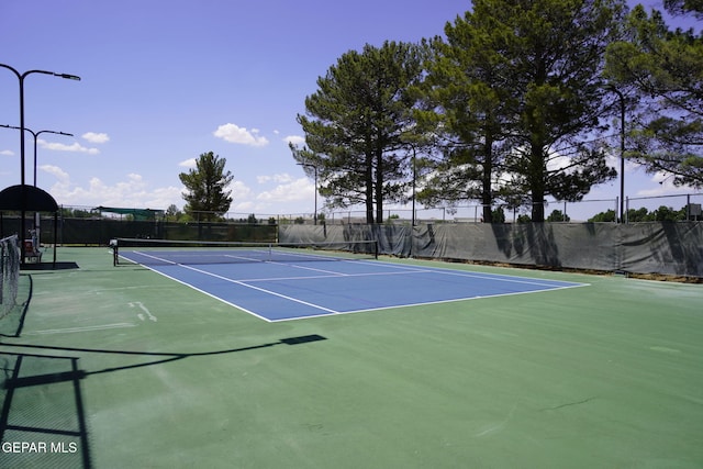 view of tennis court featuring community basketball court and fence