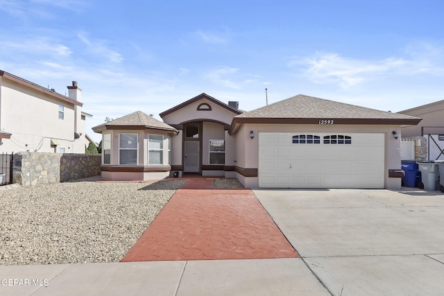 view of front of home featuring a garage, concrete driveway, roof with shingles, and stucco siding